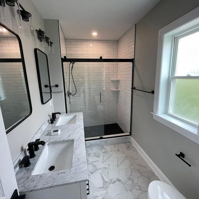 Bathroom with marble-look porcelain floor tile and a glass-enclosed subway tile shower