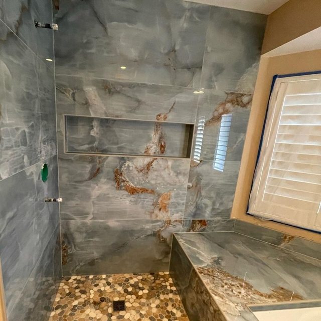 Marble-look porcelain shower with built-in bench, long niche and pebble floor