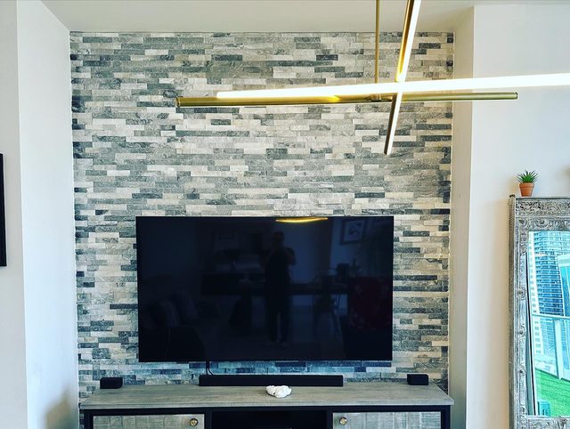 Stone and glass mosaic tile accent wall behind a TV