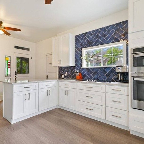 Tile backsplash: blue glass herringbone tile, with new wood-look vinyl plank floor