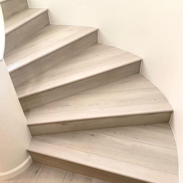 Curved staircase finished with light vinyl plank treads and white risers