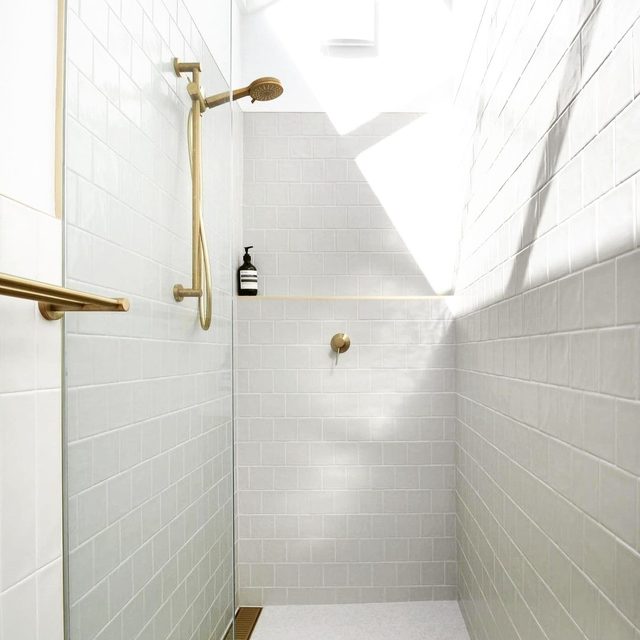 Bright white tile shower with brushed brass fixtures